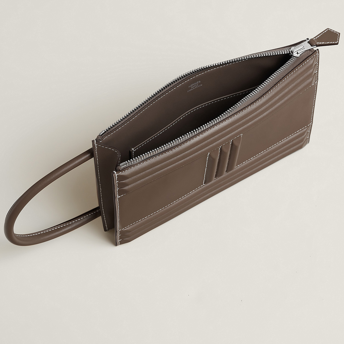 The interior of the Cadenas Clutch features a slide pocket along the rear panel and a zipper along the long side of the bag. Photo via Hermes.com.