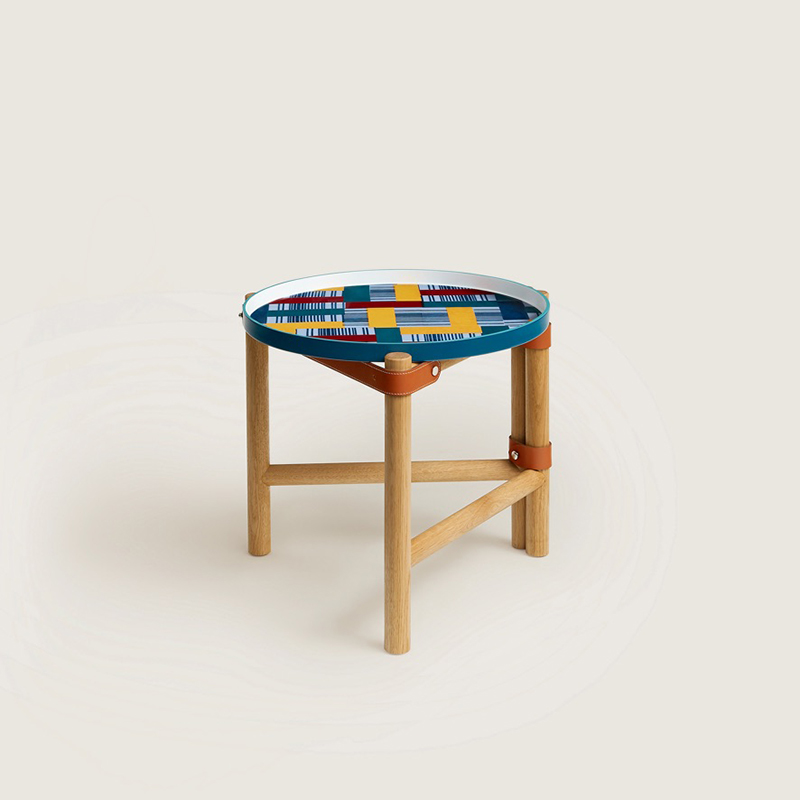 Les Trotteuses d'Hermes occasional table, large model, occasional table with a decorated porcelain tray, folding solid oak legs and bridle leather straps. Paper Block design by Gianpaolo Pagni. Measures 15.7" diameter x 14.9" high, $6,450. Photo via Hermès.com.