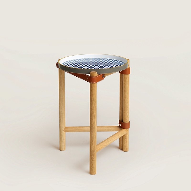 Les Trotteuses d'Hermes occasional table, small model, with a decorated porcelain tray, folding solid oak legs and bridle leather straps. H Infini design by Henri d'Origny. Measures 13.4" diameter x 19.6" high, $5650. Photo via Hermès.com.