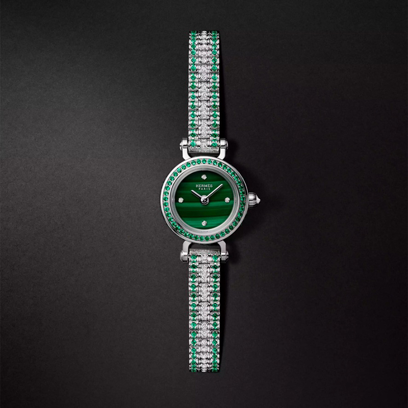 Faubourg Joailliere watch, Mini model, 15 mm, white gold bracelet set with diamonds and emeralds. 62 diamonds (0.261 ct), 90 emeralds (0.244 ct) , diamond-set malachite dial, 4 diamond chatons (0.006 ct), single tour gem-set white gold bracelet, 132 diamonds (0.52 ct), 156 emeralds (0.794 ct), $70,700. Photo via Hermès.com.
