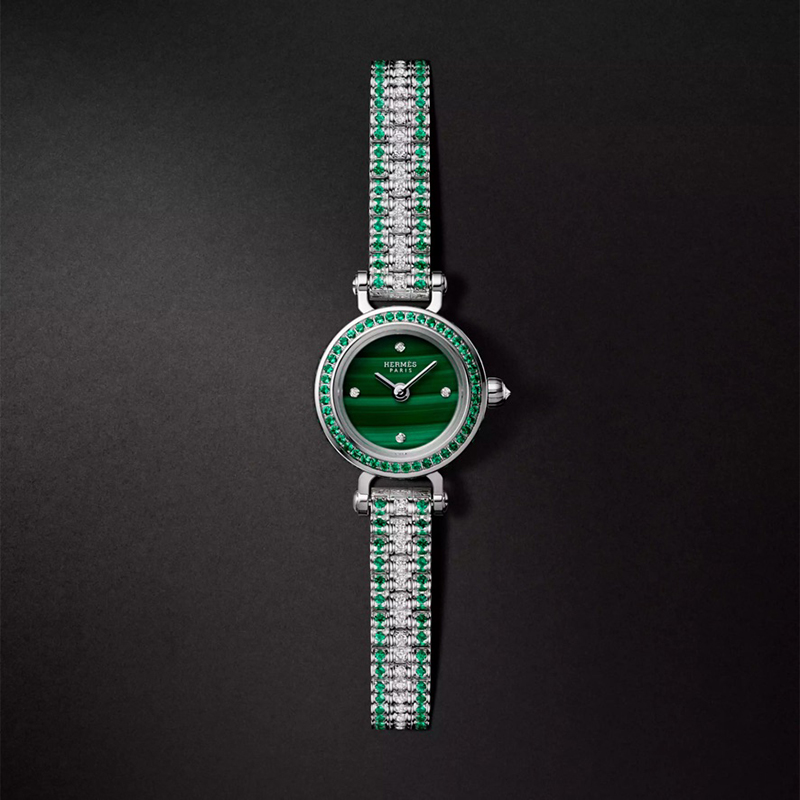 Faubourg Joailliere watch, Mini model, 15 mm, white gold bracelet set with diamonds and emeralds. 62 diamonds (0.261 ct), 90 emeralds (0.244 ct) , diamond-set malachite dial, 4 diamond chatons (0.006 ct), single tour gem-set white gold bracelet, 132 diamonds (0.52 ct), 156 emeralds (0.794 ct), $70,700. Photo via Hermès.com.